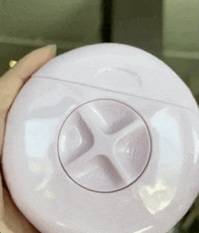 a gif of a reviewer opening the pink round razor device and turning the notch to reveal a razor, spray bottle, and bar of soap 