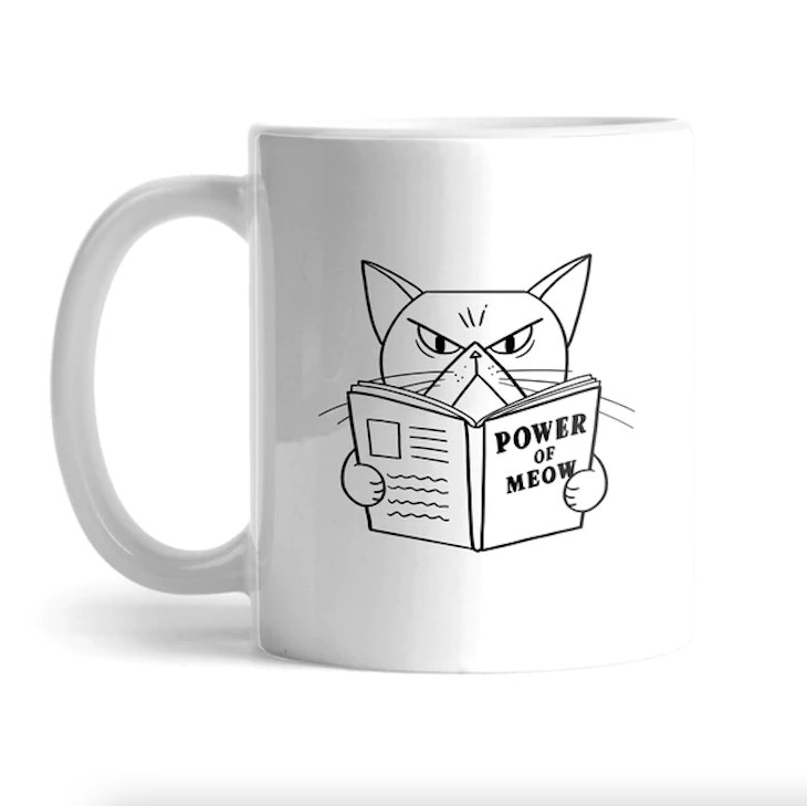 White mug with a picture of a cat reading a book that says &quot;power of meow&quot;