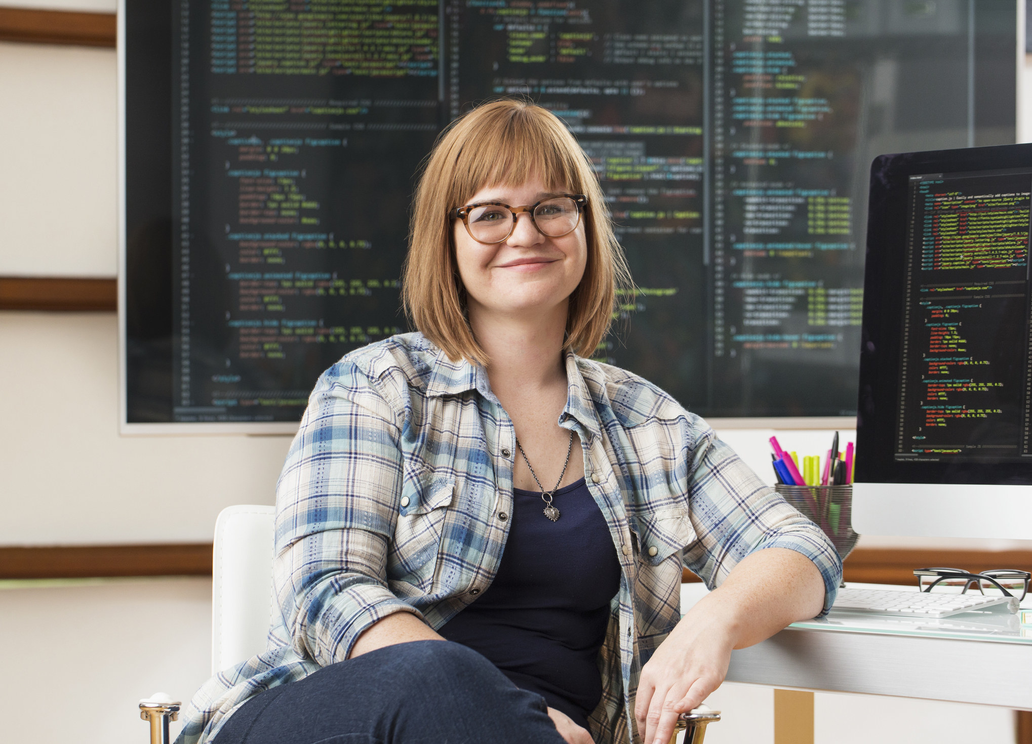 Smiling woman in front of a computer with codes on the screen