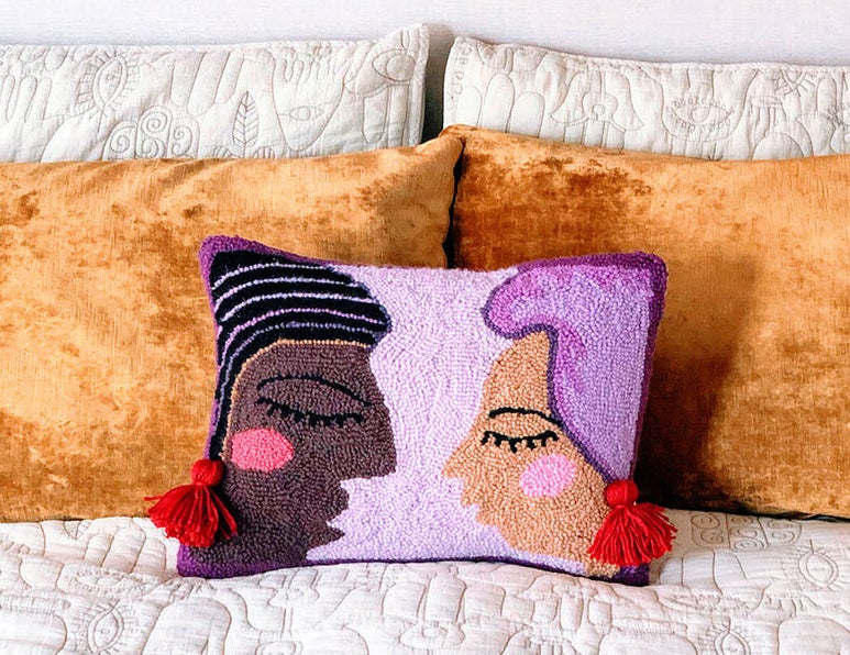 hook pillow with two womens&#x27; profiles on it who each have a tassel earring