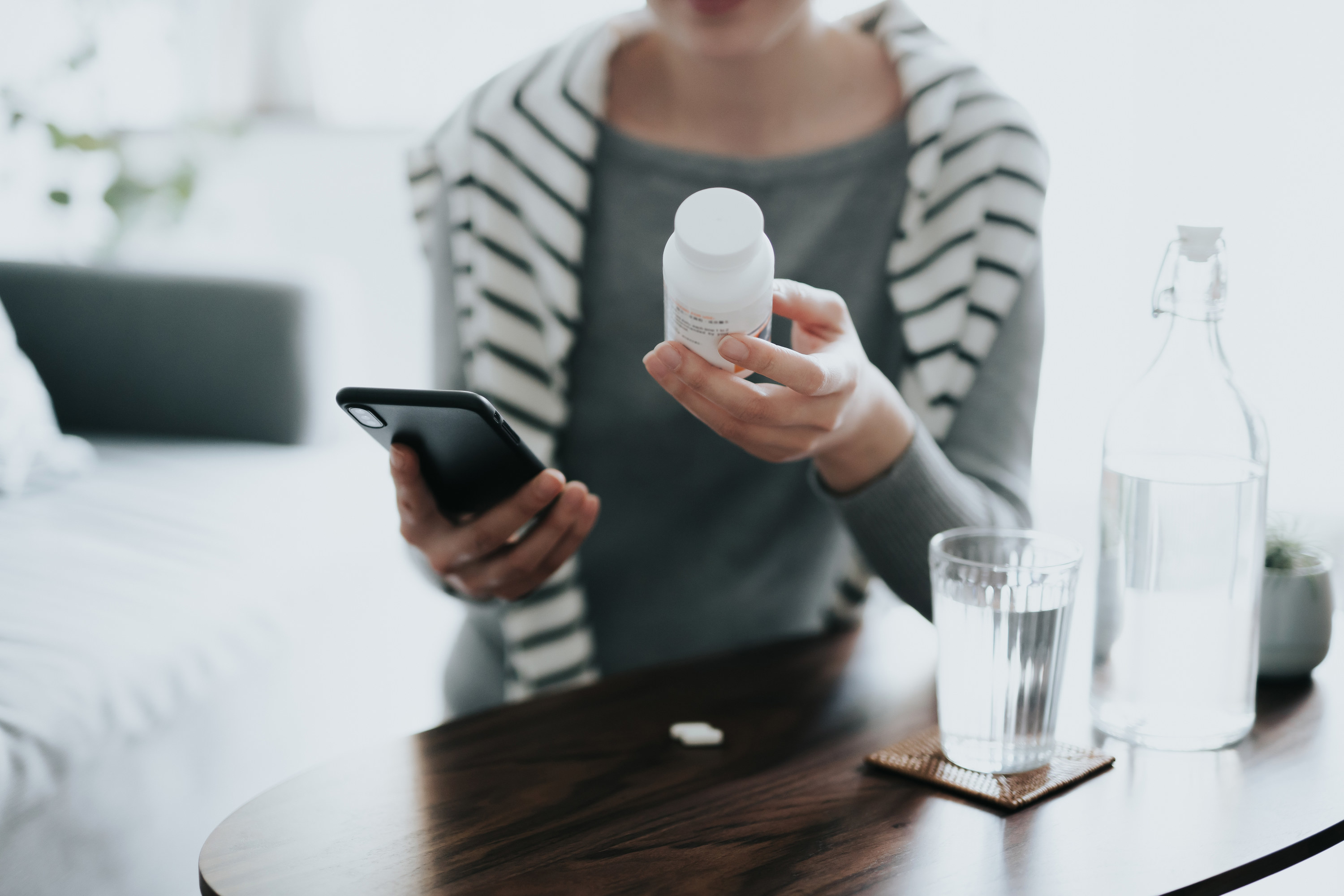 A person holding a pill bottle inside their home