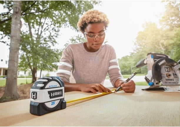 a model using the tape measure to mark a place on a board