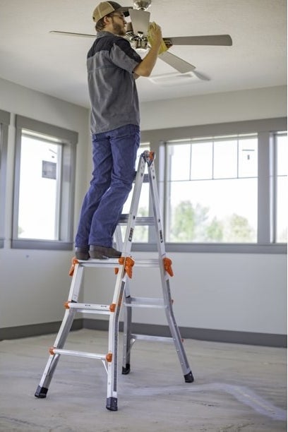 A model standing on the ladder to work on a ceiling fan