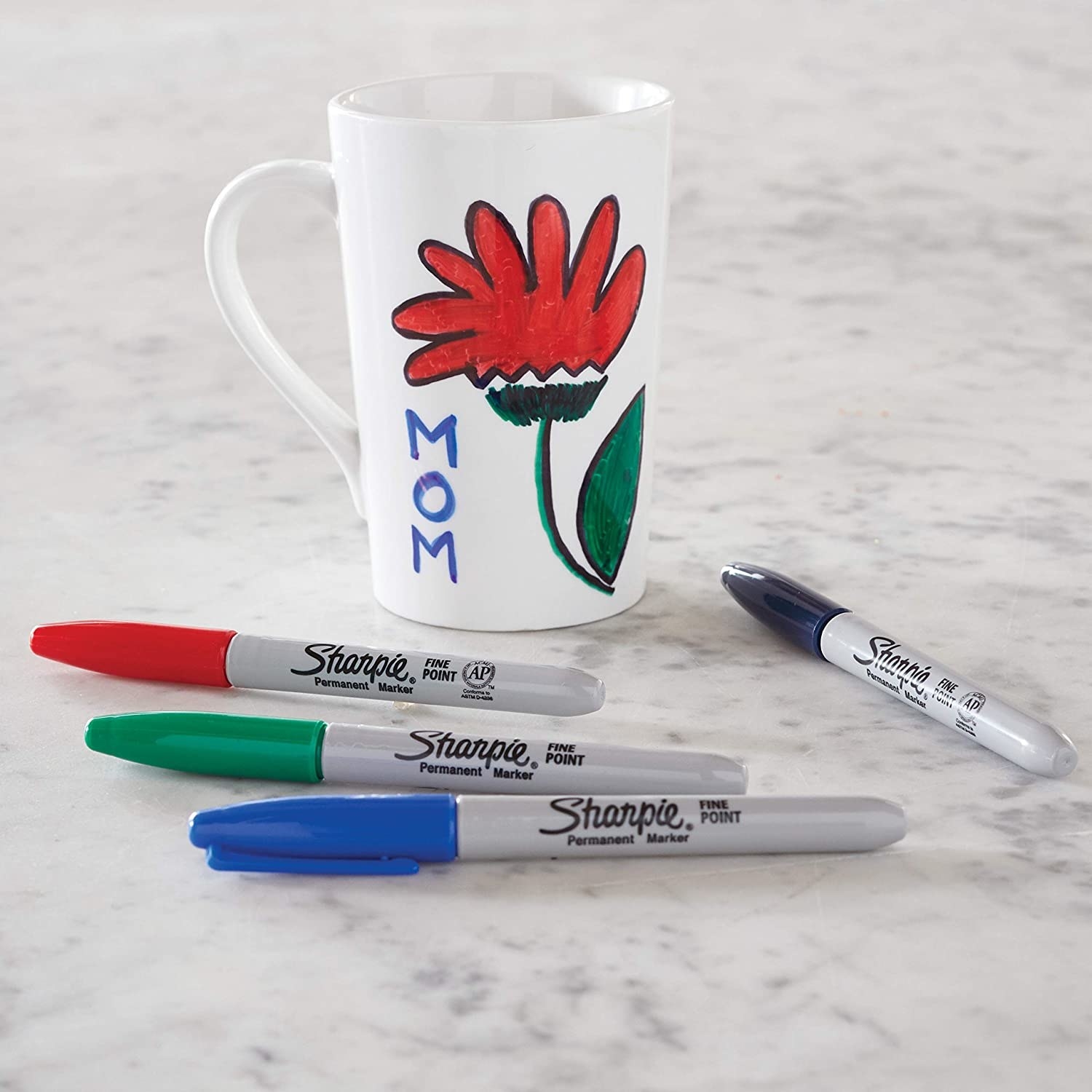 Sharpies surrounding a mug on a marble counter