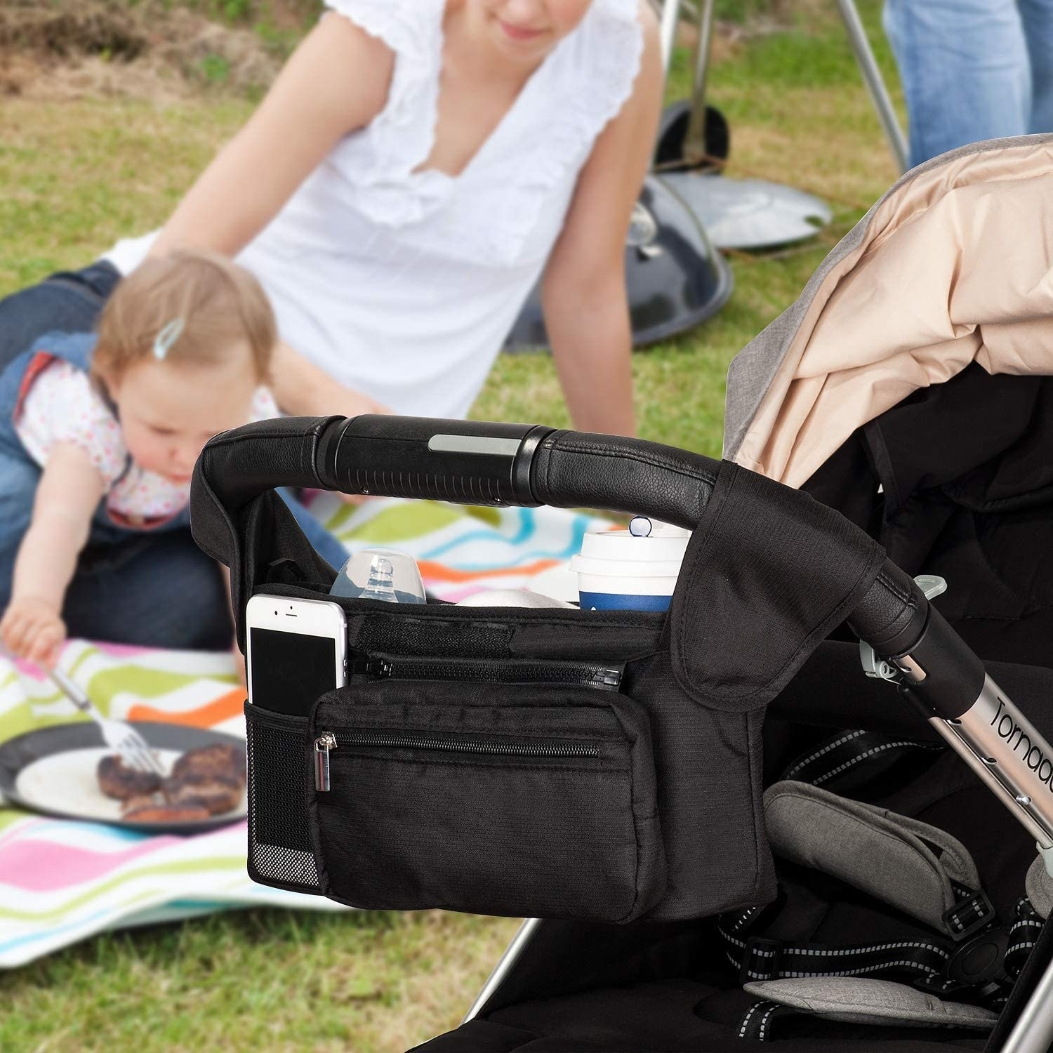 The caddy attached to a stroller with a phone in it