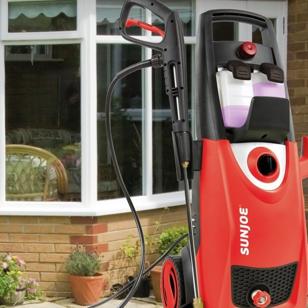 the red pressure washer in front of a brick wall with a window
