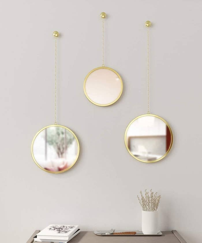 The three round mirrors hanging from chains on the wall