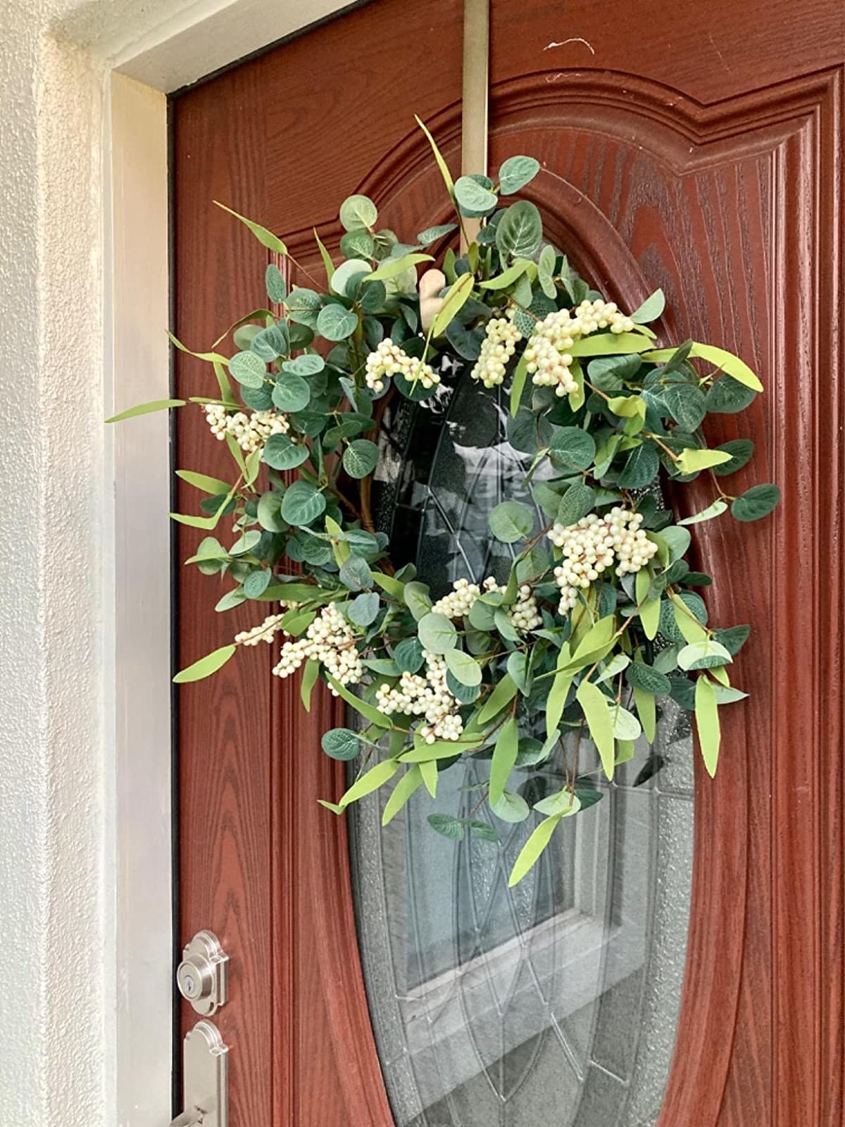a reviewer&#x27;s wreath with greenery and small white berries on a front door