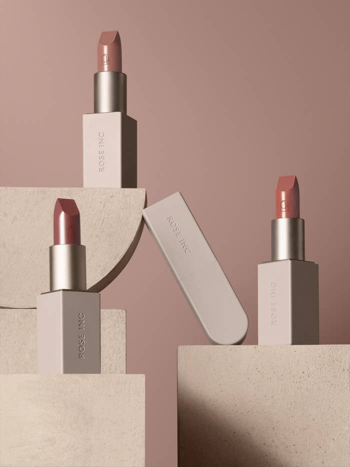 Three Rose Inc lipsticks set on earth-toned, geometric stands