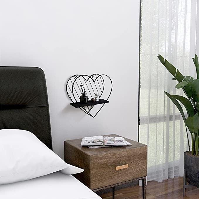 The heart shaped shelf hanging over a bedside table