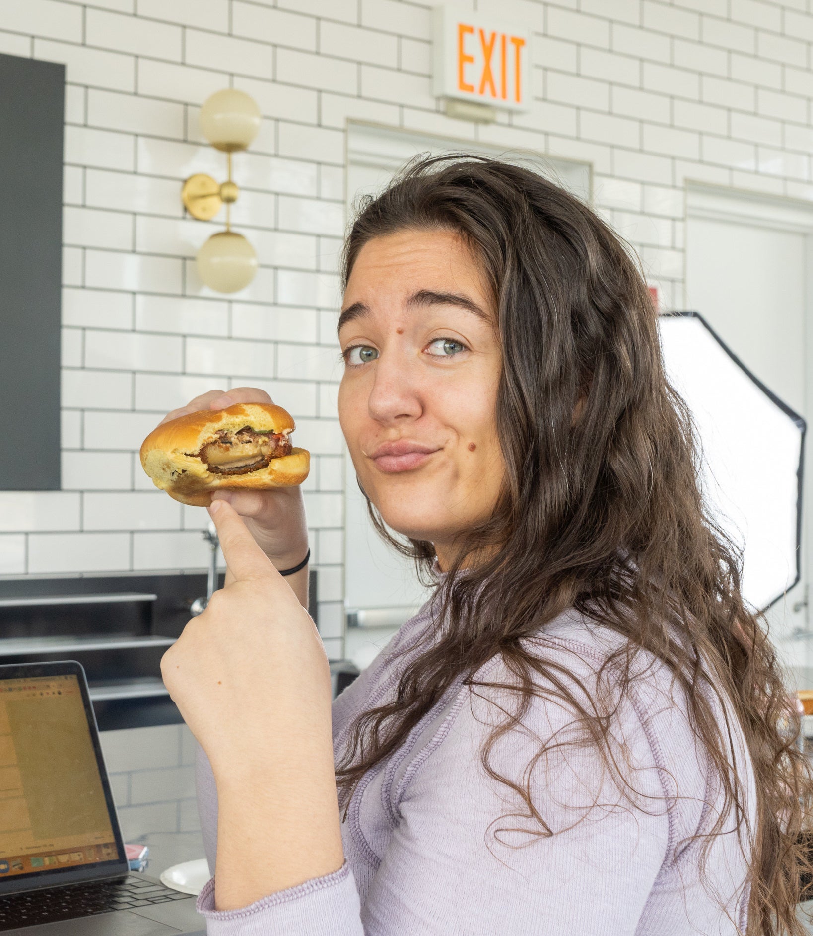 a woman pointing to the cheese inside the patty