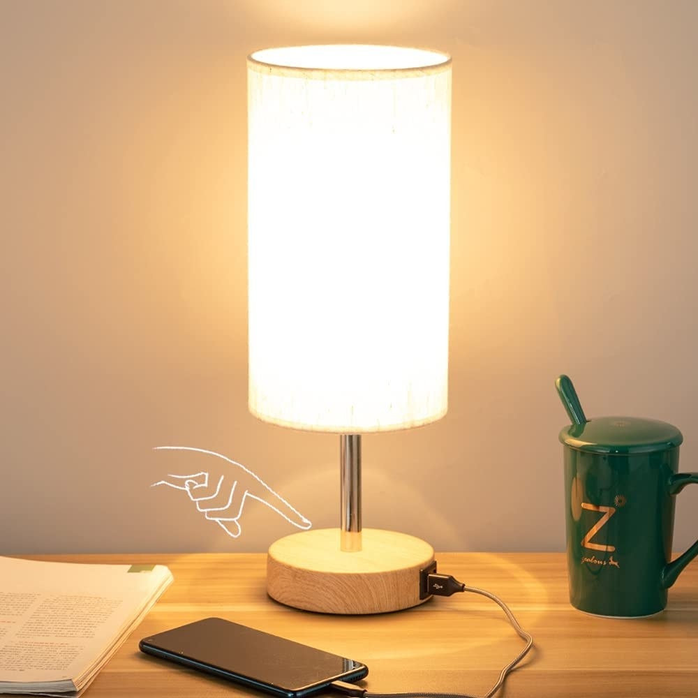 The lamp on a bedside table with a phone plugged into it
