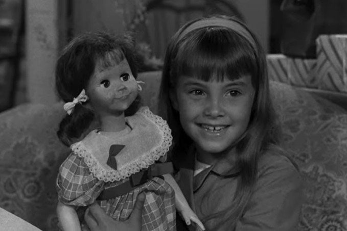 A little girl happily shows off her doll Talky Tina