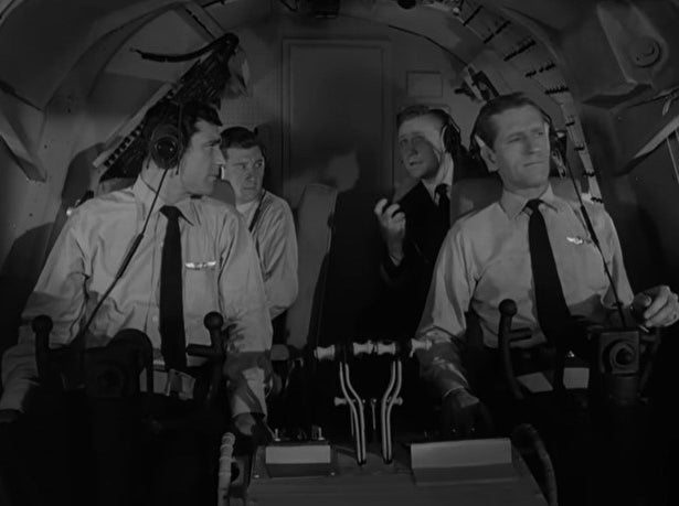 A team of four pilots sit in the cockpit discussing flight operations
