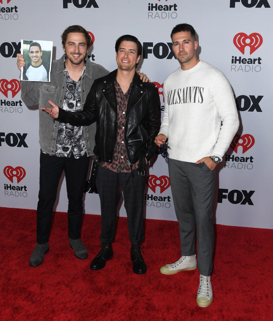 Three members of Big Time Rush dressed casually as they pose for photos on the red carpet