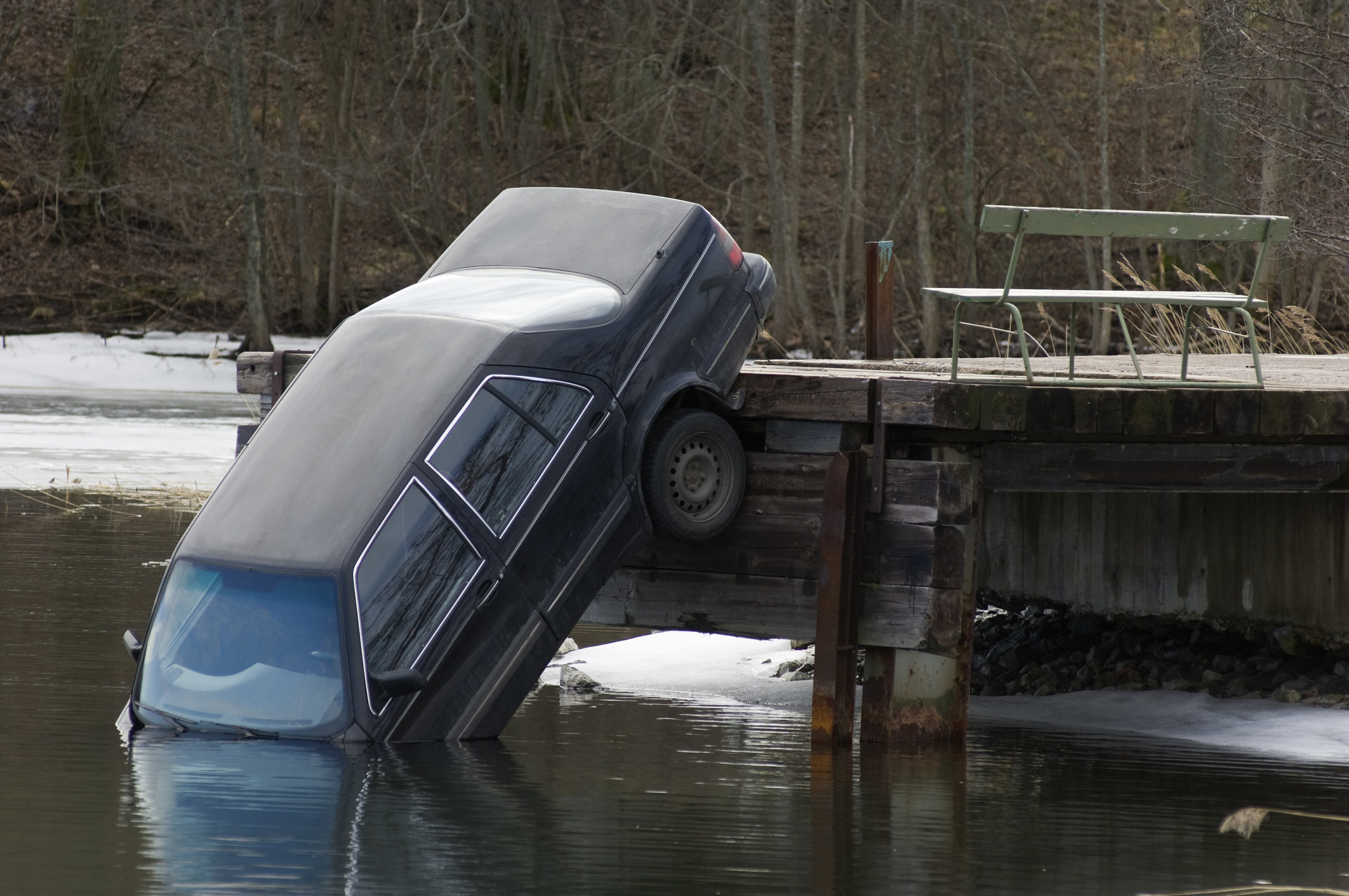 Car tipping down into a lake from the pier