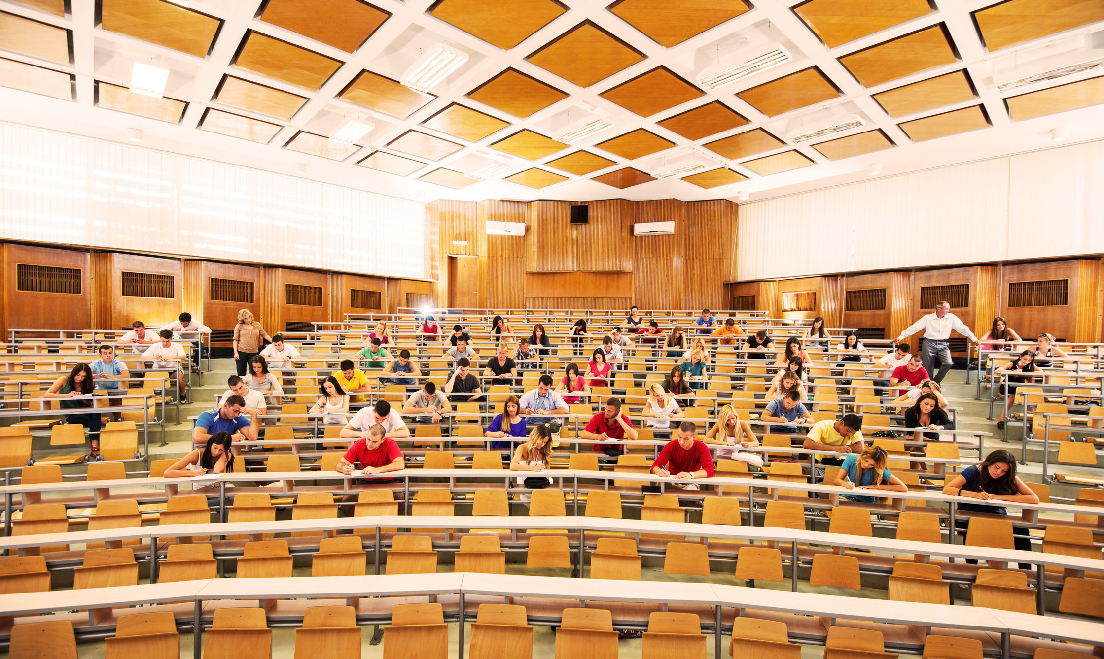 College students in the university amphitheatre sitting and taking an exam