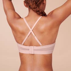 another model wearing the blush-colored bra with criss cross straps at the back