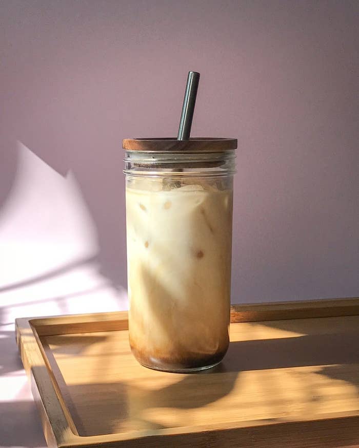 a slim glass tumbler with a bamboo lid and metal straw