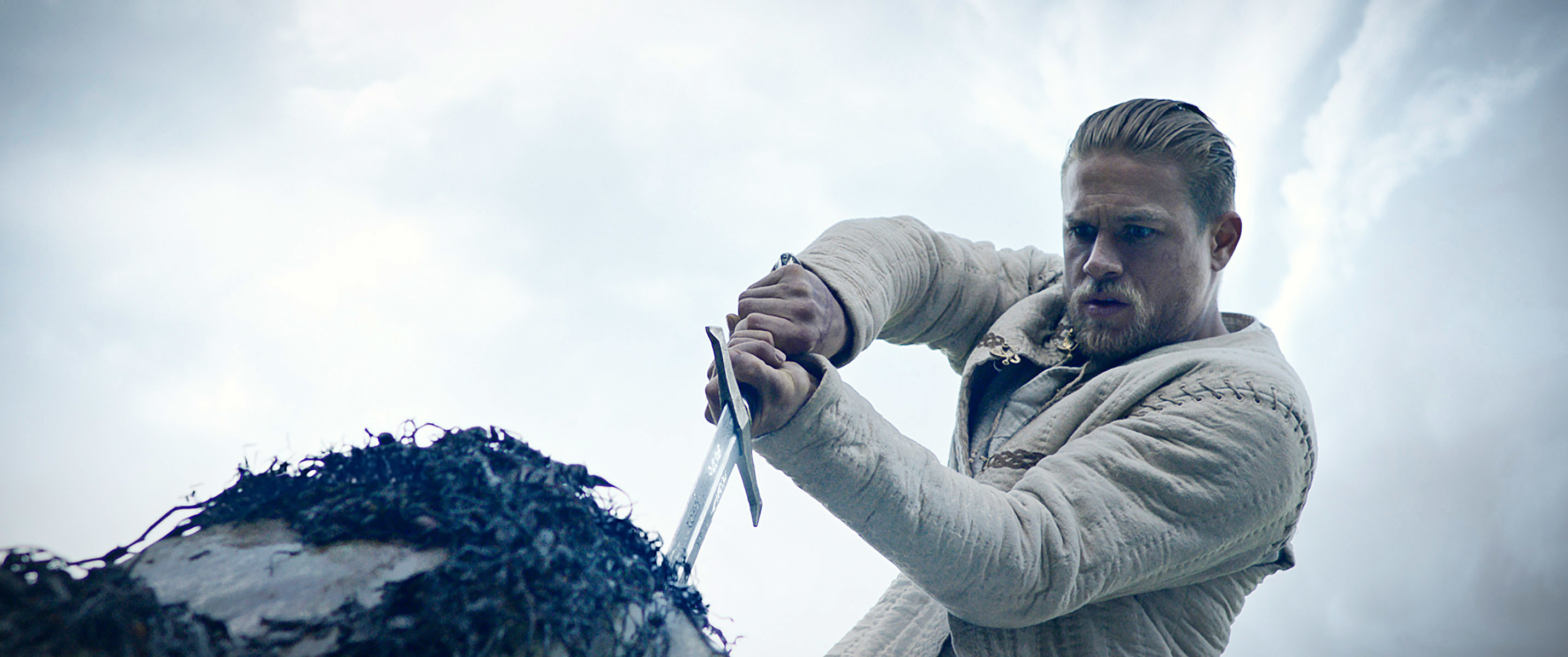Charlie Hunnam pulling a sword out of a stone in a scene from King Arthur: Legend of the Sword