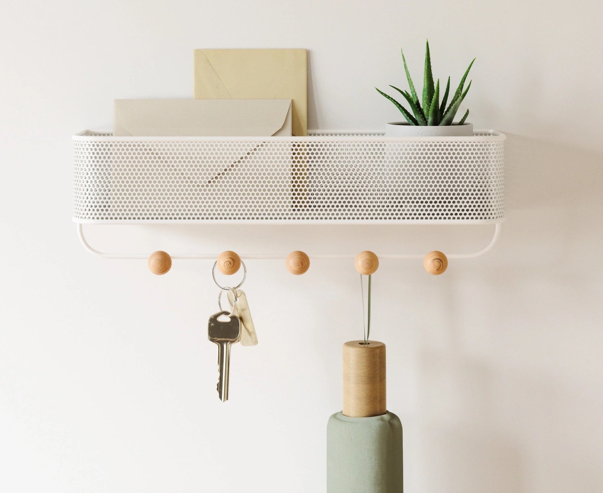 The organizer on a plain wall with keys and an umbrella hanging from it and letters on the top shelf