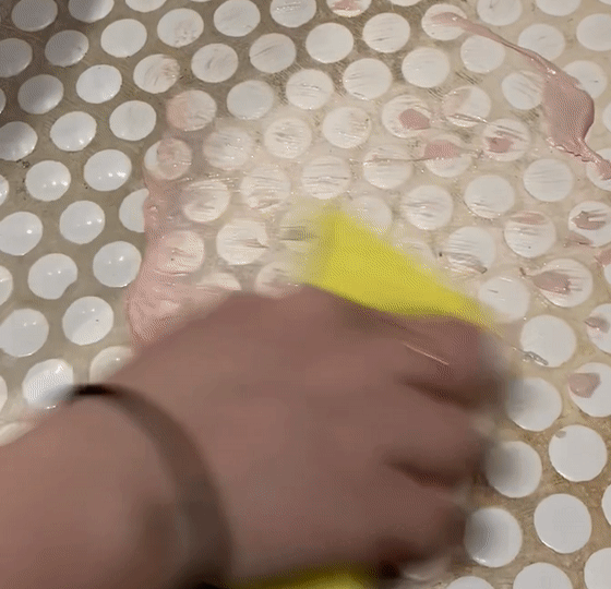 gif of Britt using the pink stuff to scrub stains off of white grout