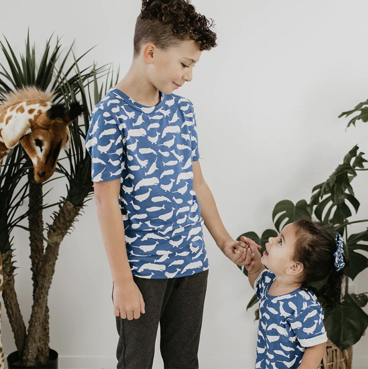 Two kids wearing matching whale print shirts