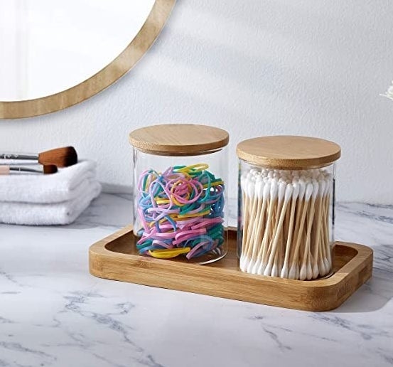 The tray with two glass jars on it on a bathroom counter