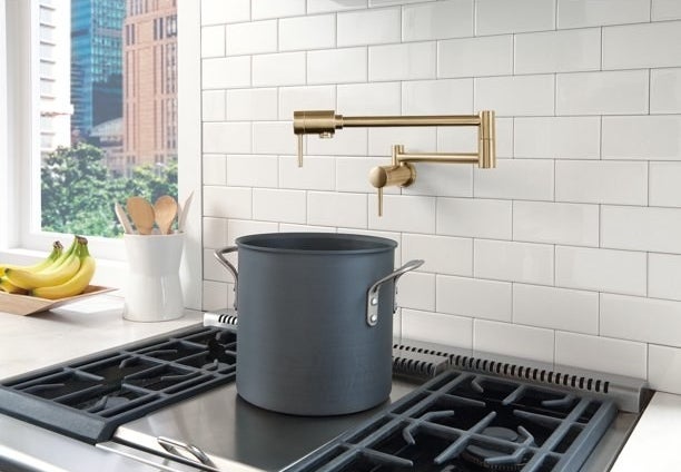 the pot filler faucet in bronze on a subway tile kitchen wall