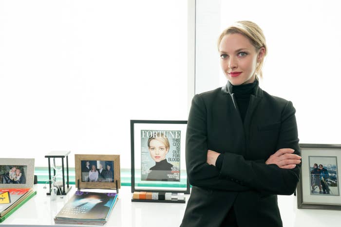 Seyfried stands next to a series of portraits