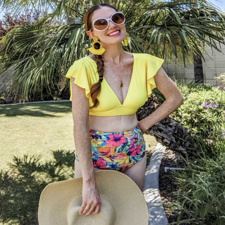 a reviewer wearing the two piece with a yellow top and floral bottom