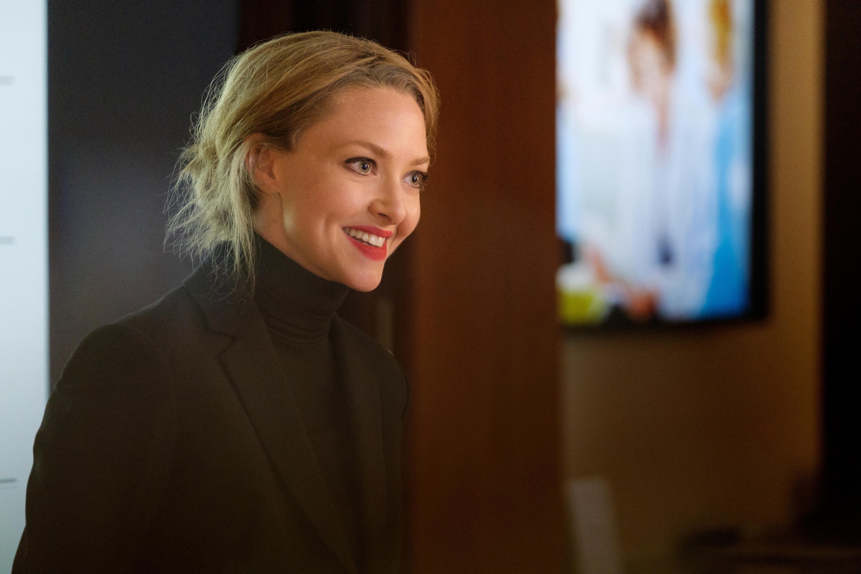 Seyfried smiles while wearing a blazer and turtleneck