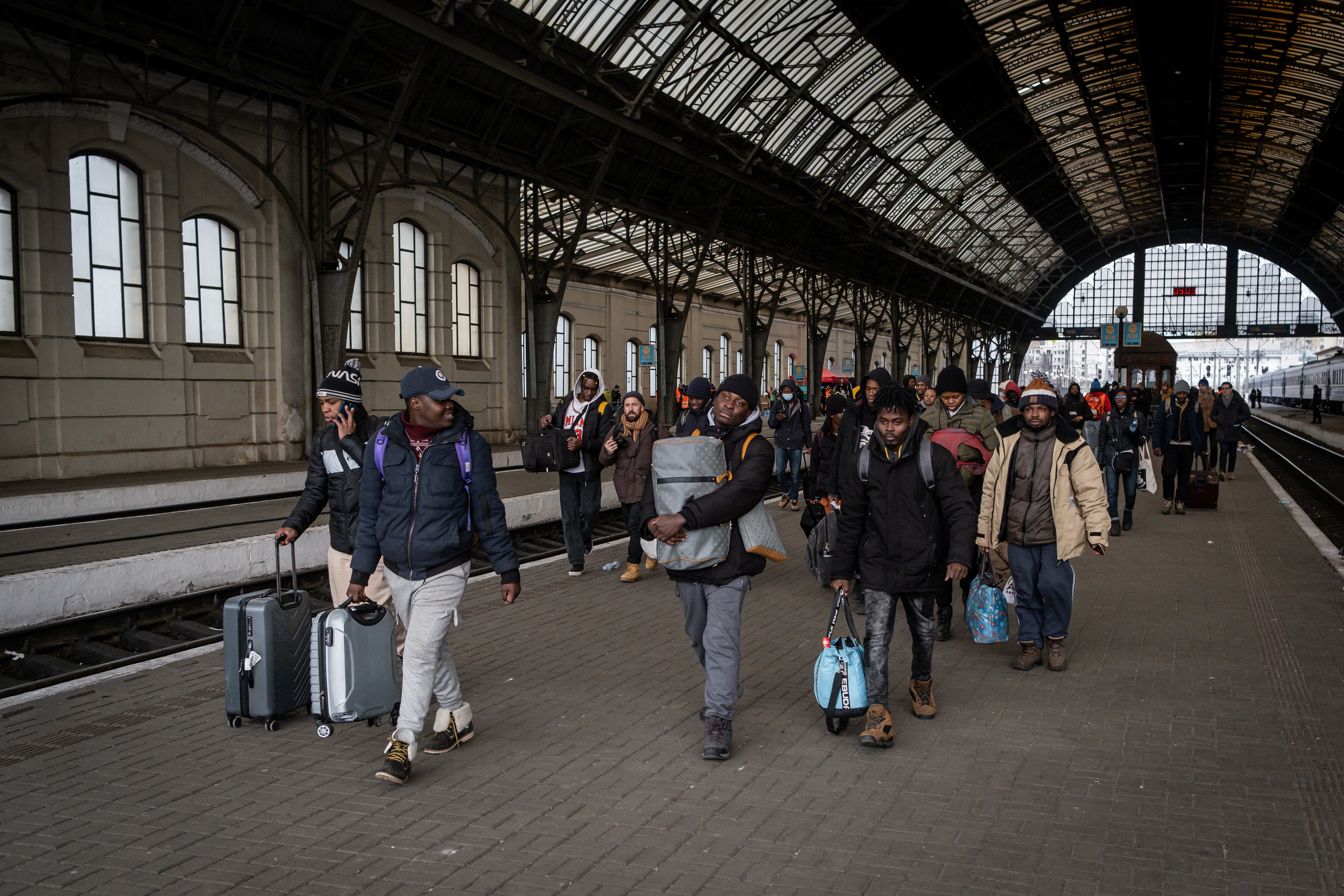 People carrying luggage and rolling suitcases walk out of a train station