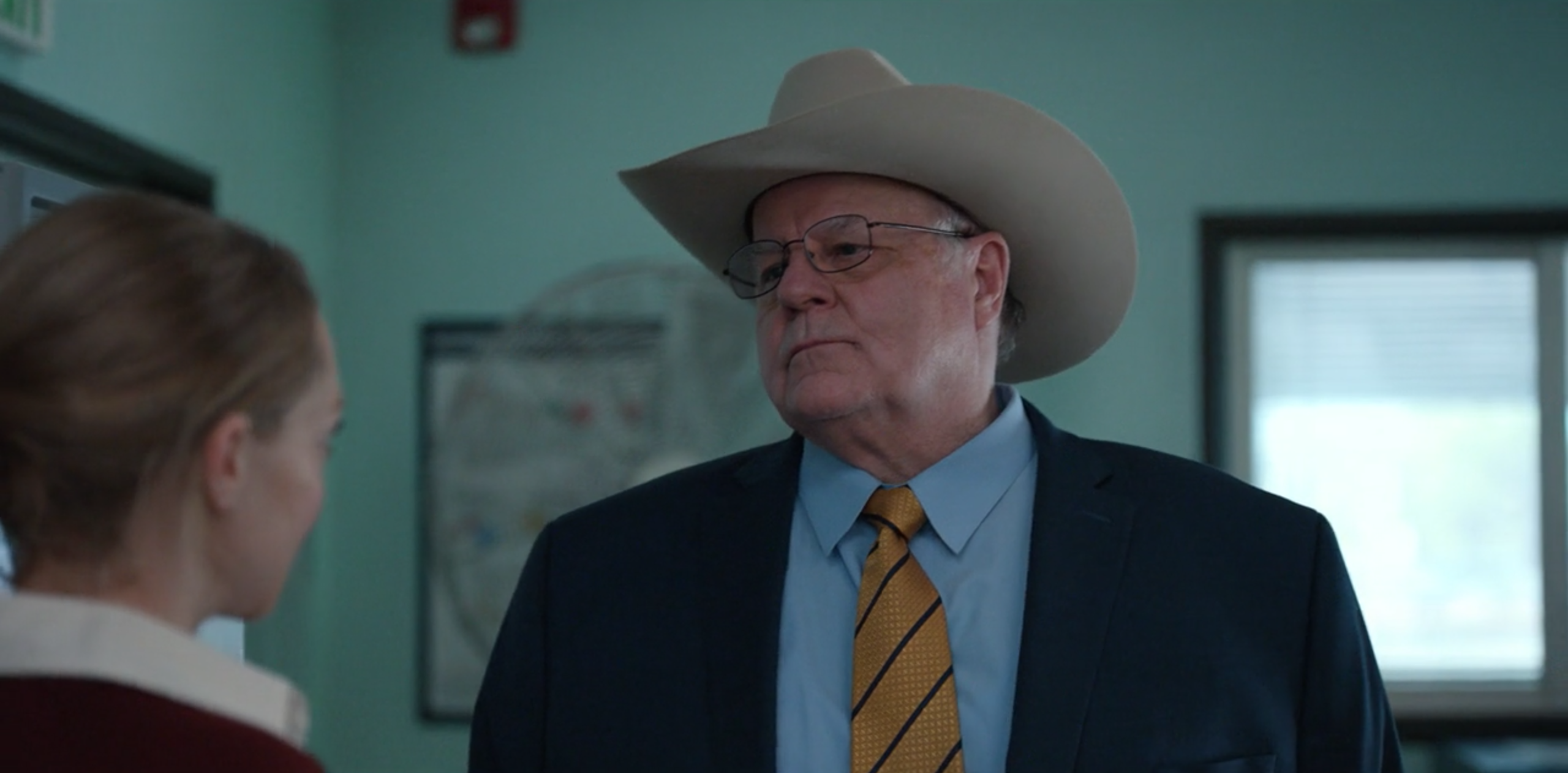 Don Lucas wearing a cowboy hat and listening intently to Elizabeth