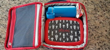 reviewer's photo of the red bag in rocket print with a lunch box and water bottle inside