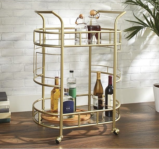 a gold bar cart with various types of alcohol displayed on top
