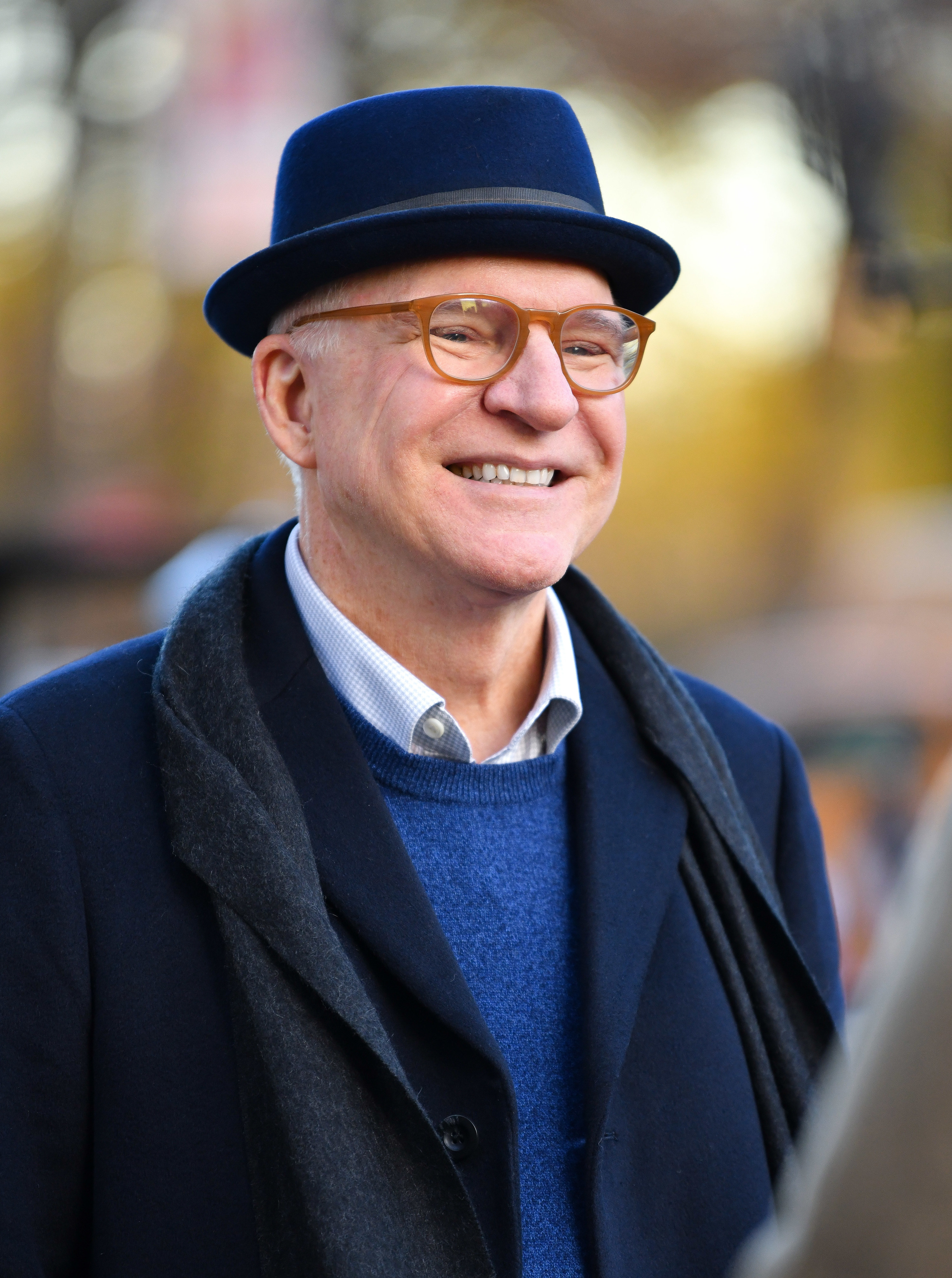 Steve Martin smiles wide while wearing a hat and glasses