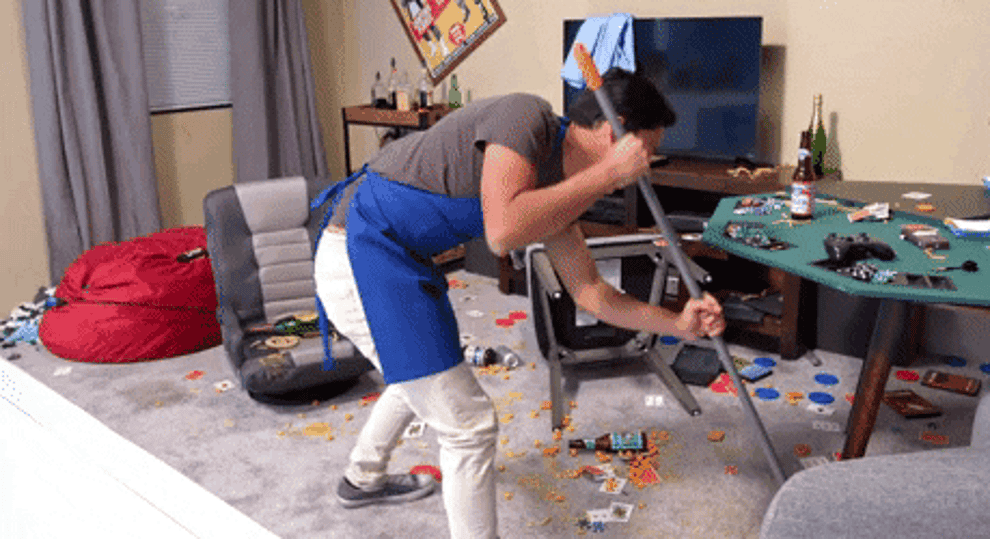gif of someone sweeping up bottles game pieces and food on a carpet floor with a broom