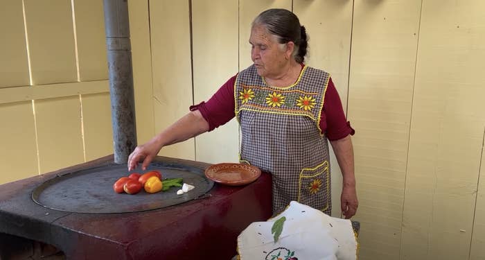 A lady preparing food with a flower apron on