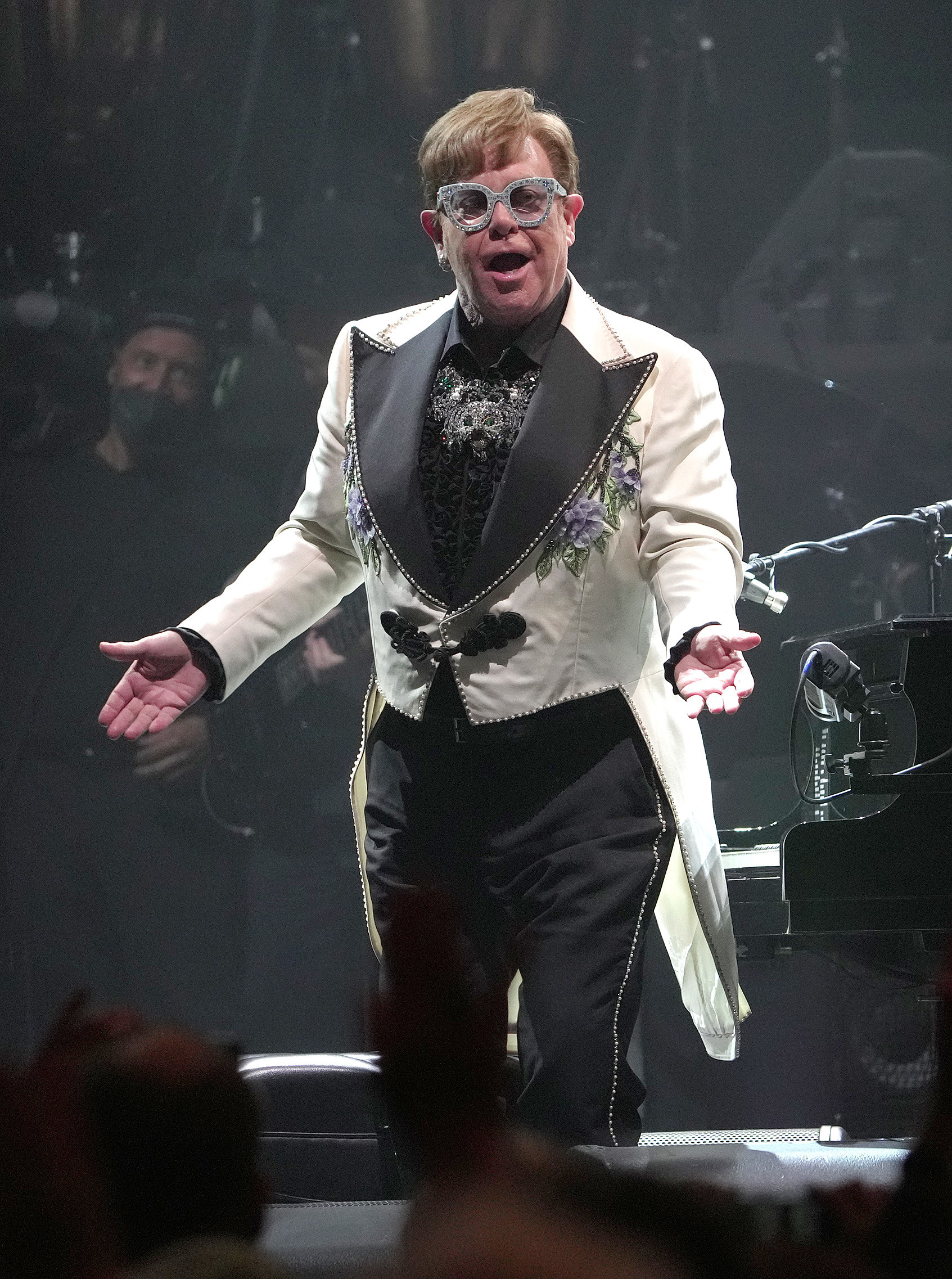 Elton John with his hands out in confusion while performing