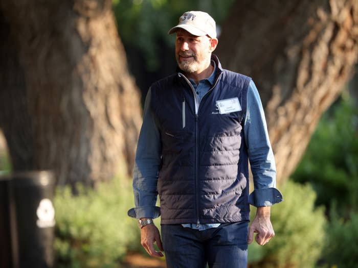 A smiling man wears a puffy vest and cap