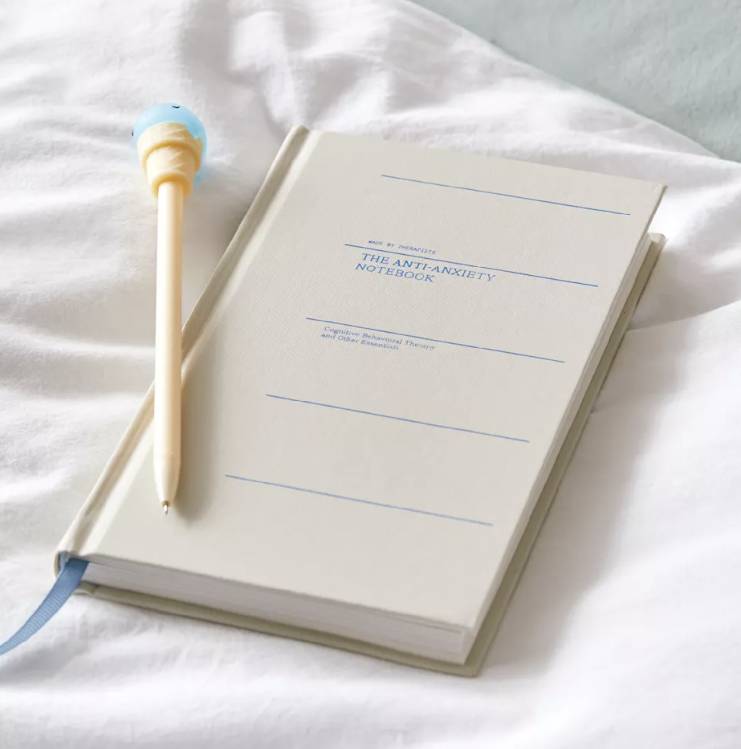 The book on a bedsheet with a pen on top of it