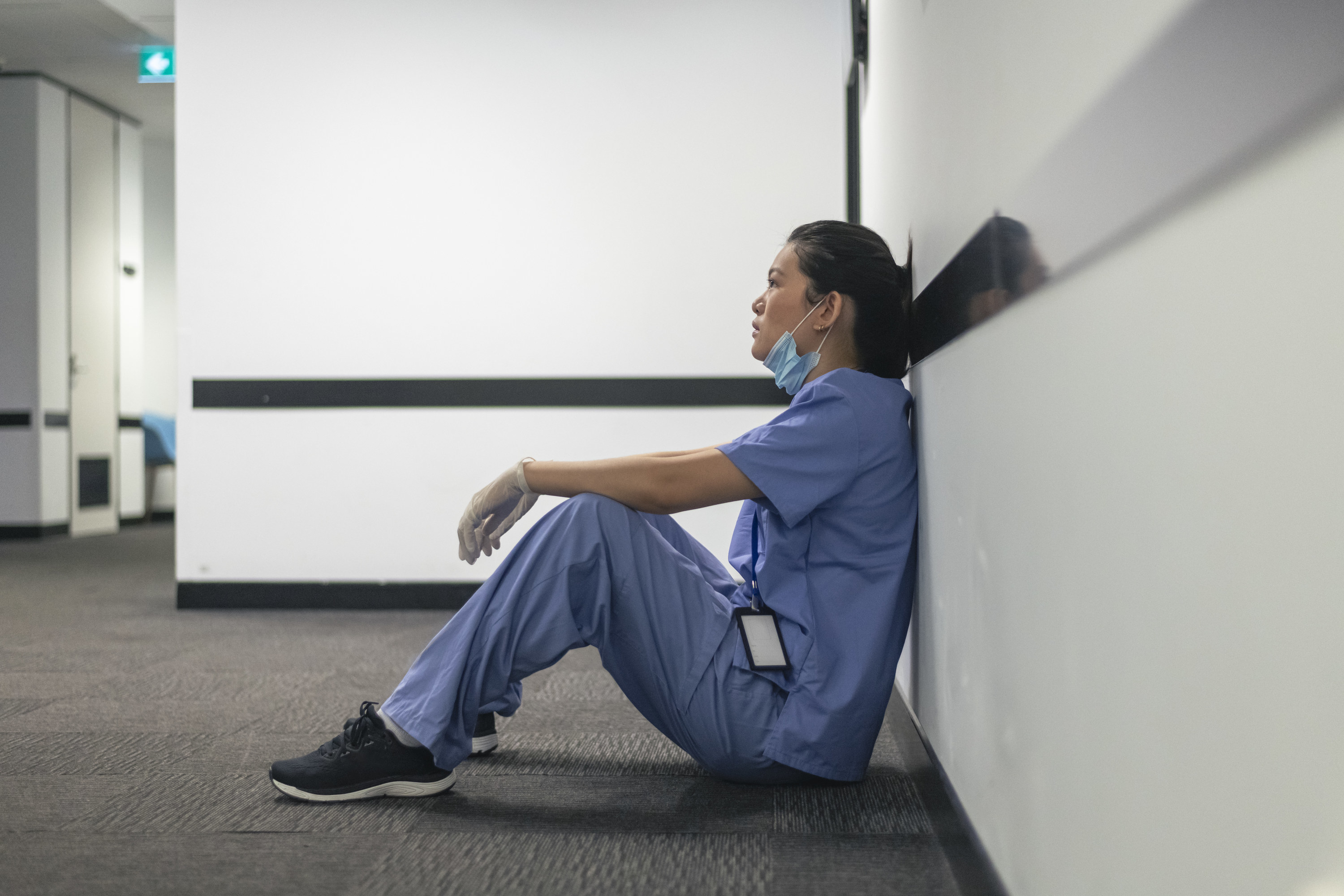 Nurse sitting on the ground with her back resting against a wall