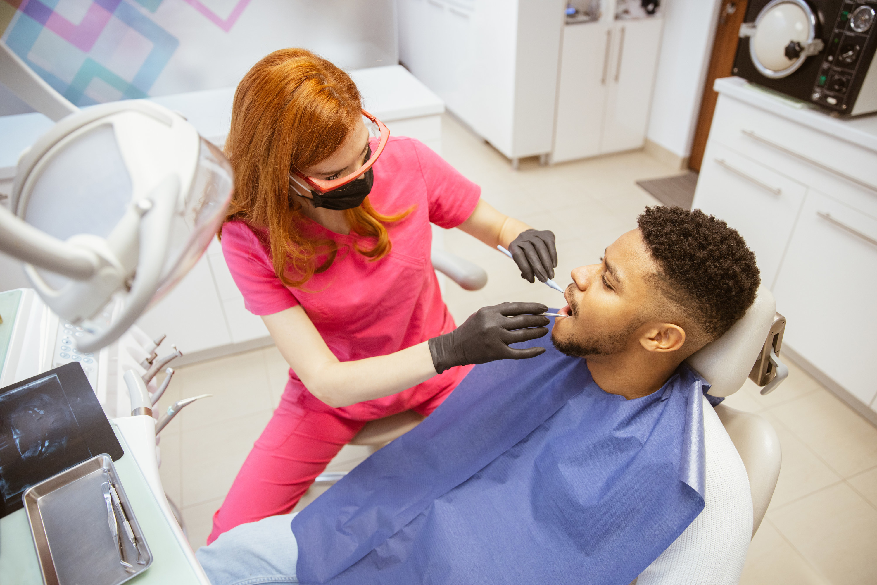 Dental hygienist working with a client wearing a blue bib