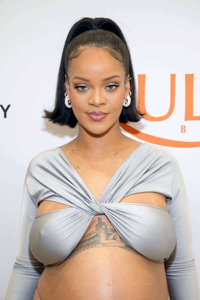 A closeup of Rihanna at her Ulta event in a twisted crop top and showing off her belly