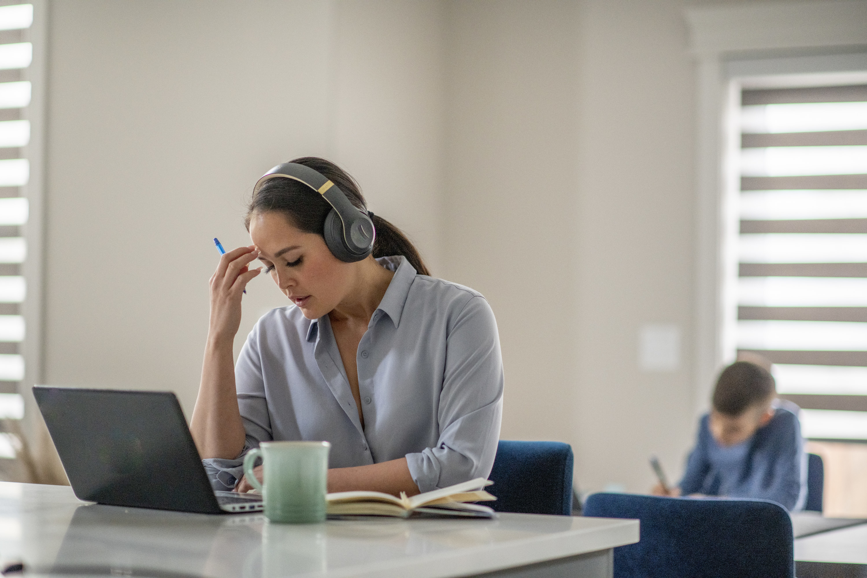 Woman looking stressed while doing work on her computer with headphones on