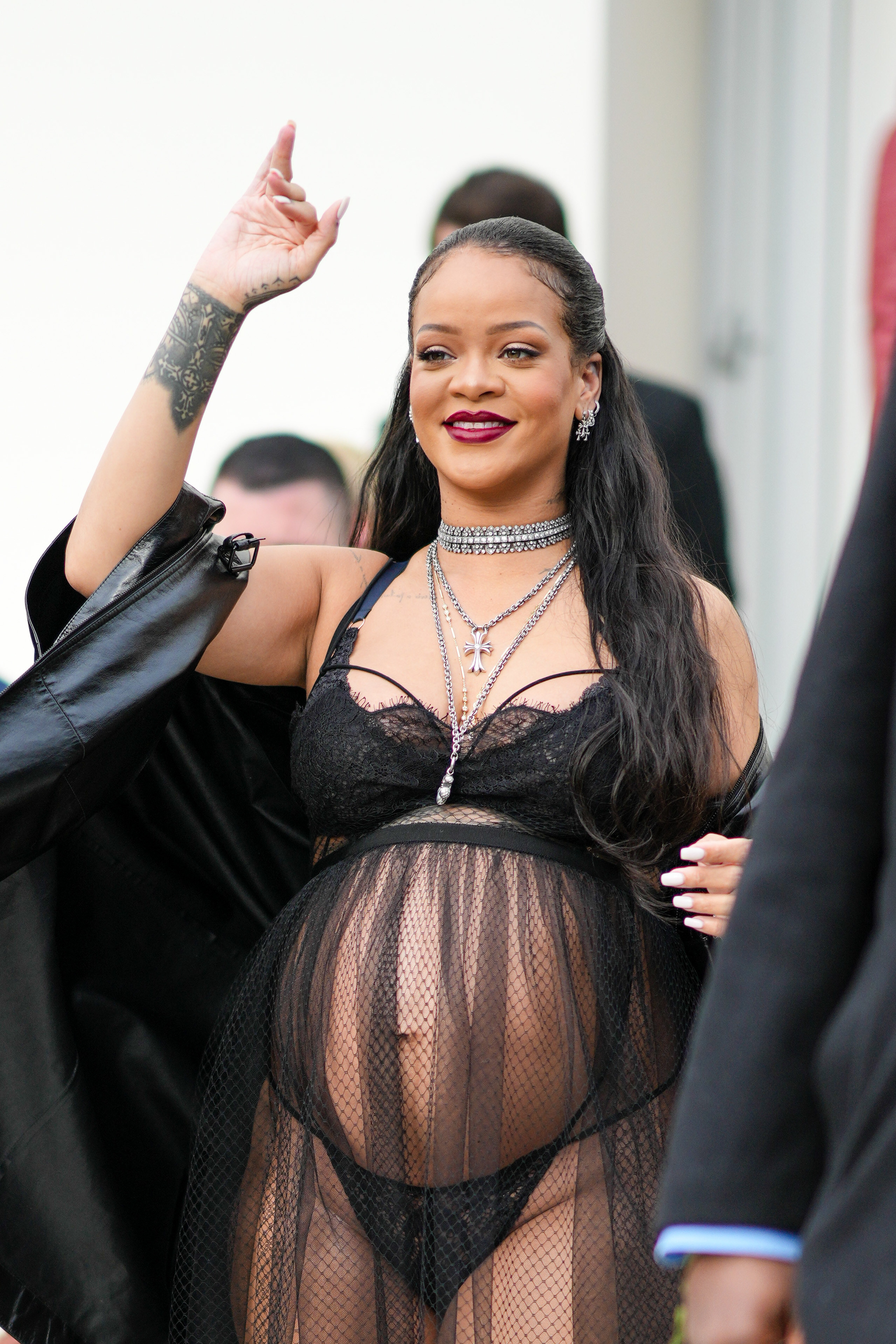 Rihanna waving at the Dior show while wearing see-through lingerie that shows off her baby bump