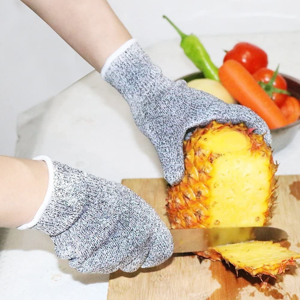 a person cutting pineapple while wearing the gloves