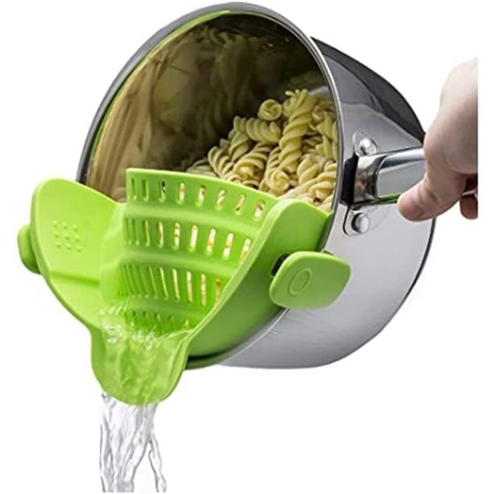 The green strainer attached to pot draining out water without any noodles escaping