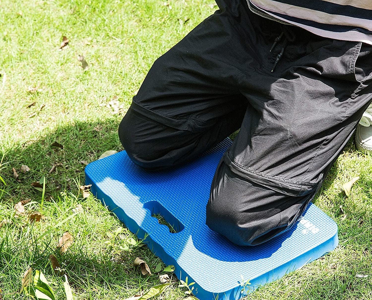 A person kneeling on the pad in a grassy yard
